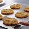Large heavy gauge aluminum cookie sheet with freshly baked cookies and wooden-handled spatula, designed for natural non-stick baking, ideal for Kitchen & Food and Baking Supplies collections.