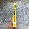 Hand holding the spine of a brightly colored yellow book titled with bold black text, part of Books, Farm and Livestock Books, Chicken Accessories, and Best Sellers collections.