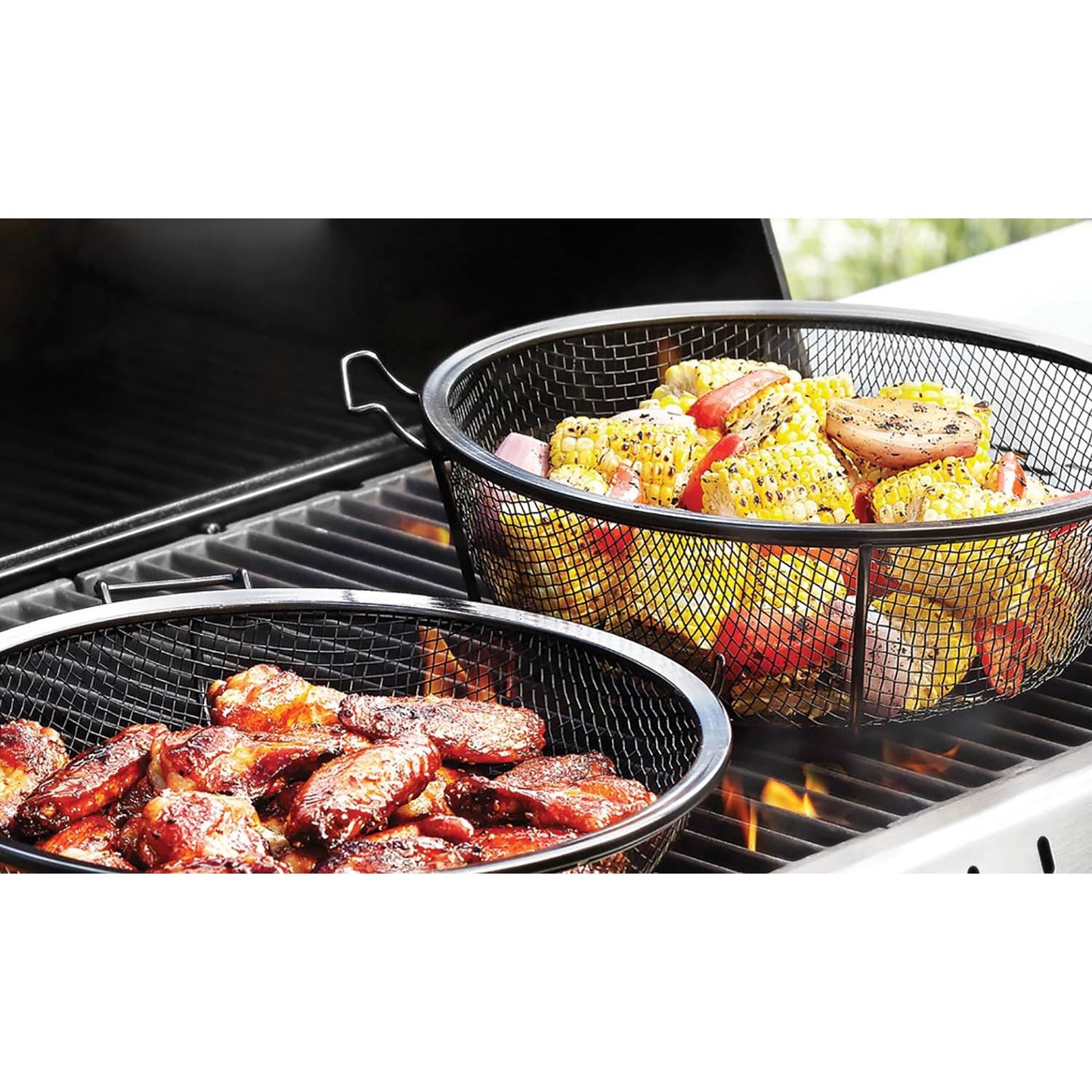 Two black metal grilling baskets on an outdoor gas grill cooking seasoned chicken wings and mixed vegetables including corn, tomatoes, and onions, ideal for versatile grilling in cookware and grilling collections.