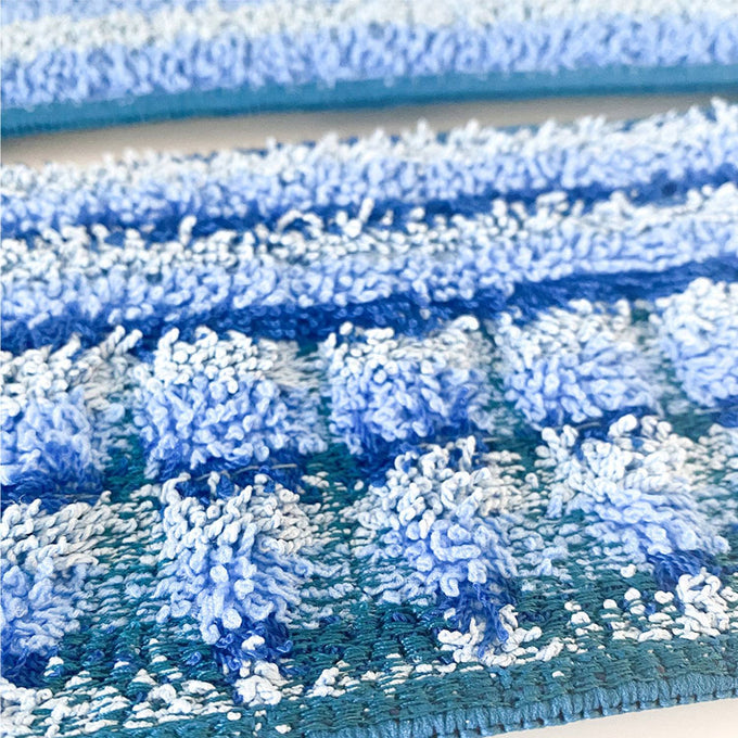 Close-up of textured blue and teal microfiber cleaning pads with looped fibers designed for scrubbing and polishing hard floors, featured in household cleaning and best sellers collections.