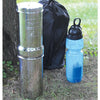 Compact polished stainless steel portable water filtration system with black carrying bag and blue sports bottle, ideal for camping, emergency supplies, and outdoor use.