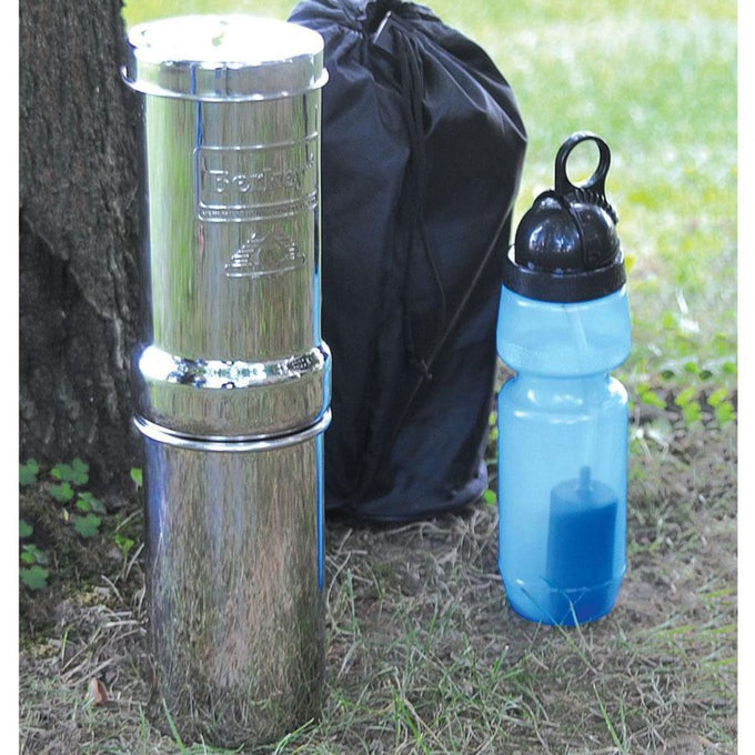 Compact polished stainless steel portable water filtration system with black carrying bag and blue sports bottle, ideal for camping, emergency supplies, and outdoor use.