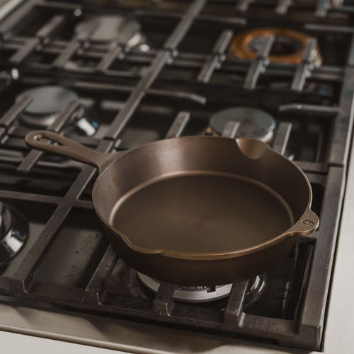 Handcrafted lightweight cast iron skillet with smooth cooking surface and dual pour spouts, made in USA, resting on a gas stove in a modern kitchen, ideal for Kitchen & Food, Camping, Cast Iron, Cookware, USA Made, and Best Sellers collections.