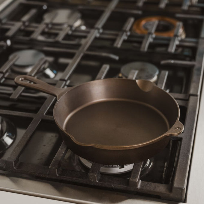 Handcrafted lightweight cast iron skillet with smooth cooking surface and dual pour spouts, made in USA, resting on a gas stove in a modern kitchen, ideal for Kitchen & Food, Camping, Cast Iron, Cookware, USA Made, and Best Sellers collections.
