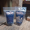 Two resealable bags of handcrafted chocolate-covered peanuts, one labeled dark double dipped and the other milk chocolate, placed on rustic wooden surface, USA made snack.