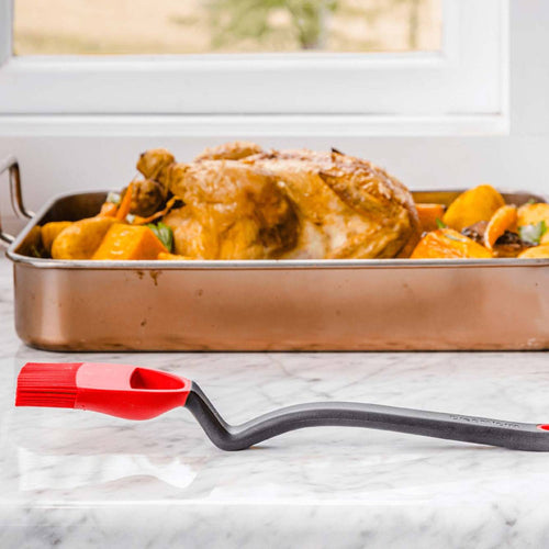 Silicone basting brush with angled black handle and red flexible head designed to reach tight spaces for basting roasted chicken and vegetables, perfect for Kitchen Gadgets and Grilling collections.