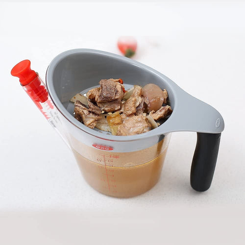 Clear plastic fat separator with soft black grip handle, gray rim, red stopper, and measurement markings, filled with meat drippings and solids, ideal for Kitchen & Food, Kitchen Gadgets, Cooking and Baking Helpers, Best Sellers, and Promo Eligible collections.
