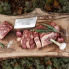 Handcrafted cleaver knife with a sturdy hardened blade and wooden handle resting on a rustic wooden board next to fresh sliced meat, garlic, shallots, and rosemary, suited for butchering, camping, and kitchen food prep in Farm, Garden & Tool and Specialty Equipment collections.