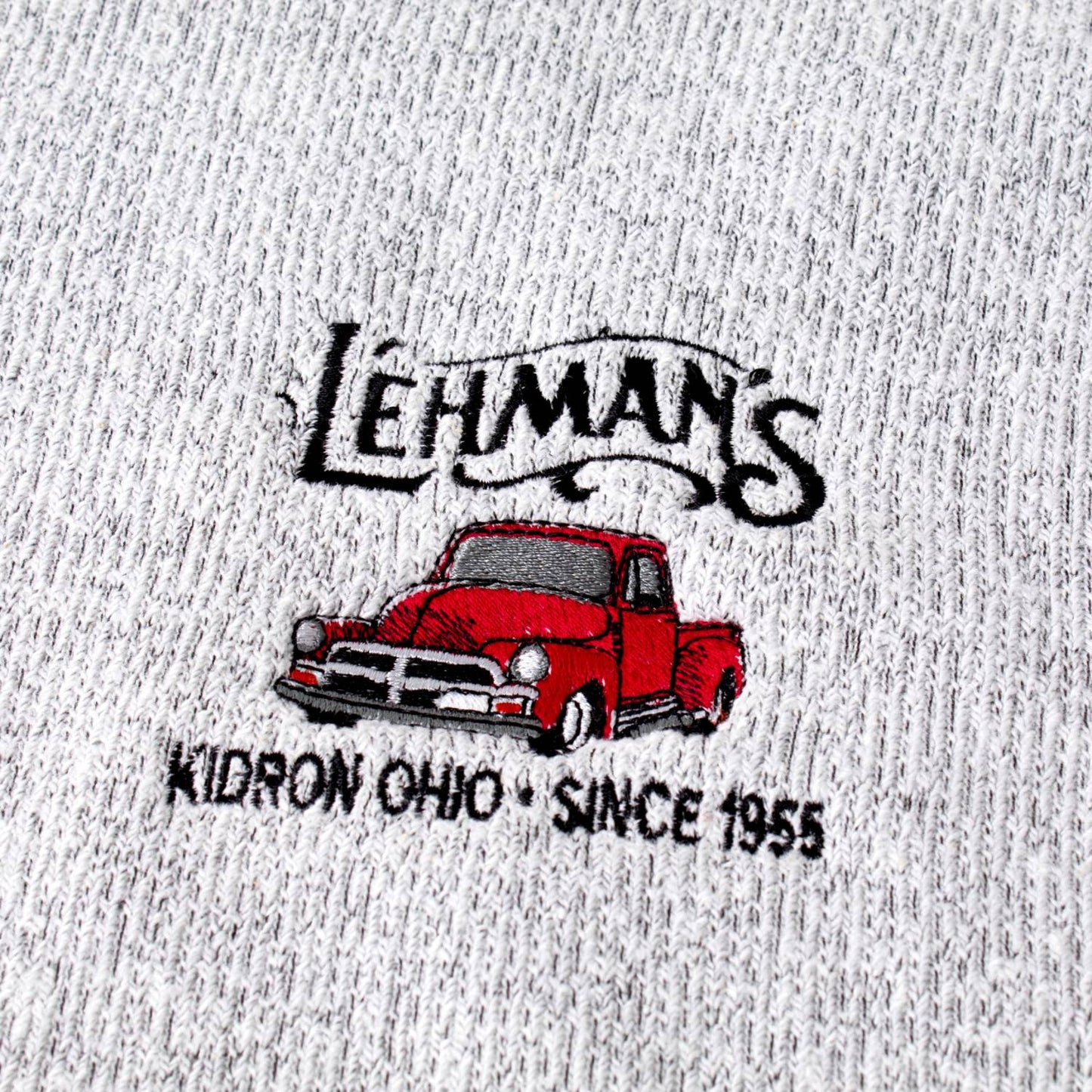 Close-up of a handcrafted sweatshirt fabric embroidered with a vintage red truck and Lehman’s logo, highlighting unique details in Health & Wellness, Clothing and Accessories, Best Sellers, and Promo Eligible collections.