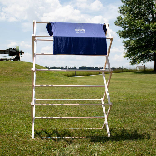 Handcrafted small wooden floor clothes dryer standing outdoors on a grassy field, holding a blue garment, highlighting Amish made, USA made, and best sellers in Home & Decor and Laundry Supplies collections.