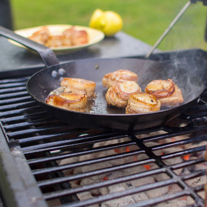 Lodge seasoned steel skillet with long handle cooking seared bacon-wrapped medallions over an outdoor grill, perfect for Kitchen & Food, Cookware, Pots and Pans, USA Made, Best Sellers collections.