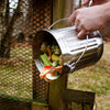 Brushed stainless steel compost pail with sturdy handle being emptied outdoors, designed for odor-free food scrap collection in Farm, Garden & Tool and Kitchen & Food collections.