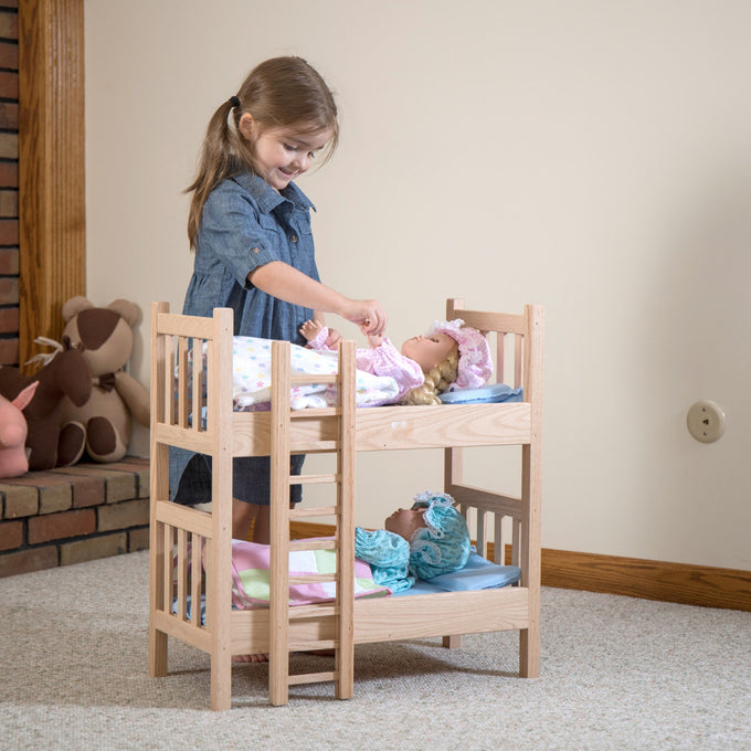 Young girl playing with handcrafted solid oak doll bunk beds holding two dolls dressed in pastel pajamas, featured in Toys, Books & Games, Amish Made, USA Made collections.