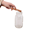 Handcrafted oak jar opener held above a clear glass Mason jar, designed by Amish artisans for easy removal of canning lids, featured in Kitchen & Food and Canning Accessories collections.