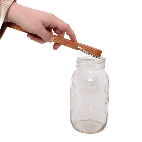 Handcrafted oak jar opener held above a clear glass Mason jar, designed by Amish artisans for easy removal of canning lids, featured in Kitchen & Food and Canning Accessories collections.