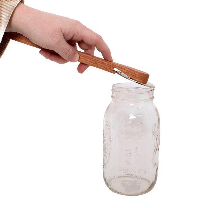 Handcrafted oak jar opener held above a clear glass Mason jar, designed by Amish artisans for easy removal of canning lids, featured in Kitchen & Food and Canning Accessories collections.