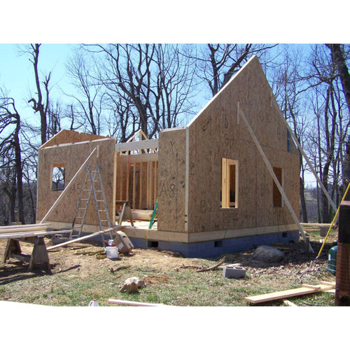 Partially constructed tiny house with plywood sheathing and framed openings, supported by timber braces, set outdoors among leafless trees, featured in Toys, Books & Games and Home and Garden How-To Books collections.