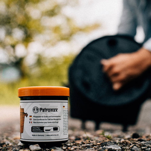Container of Petromax Care Conditioner with bright orange lid on outdoor ground, designed to preserve and protect cast iron cookware, featured in Kitchen & Food, Cookware, Cast Iron, Best Sellers, and Promo Eligible collections.