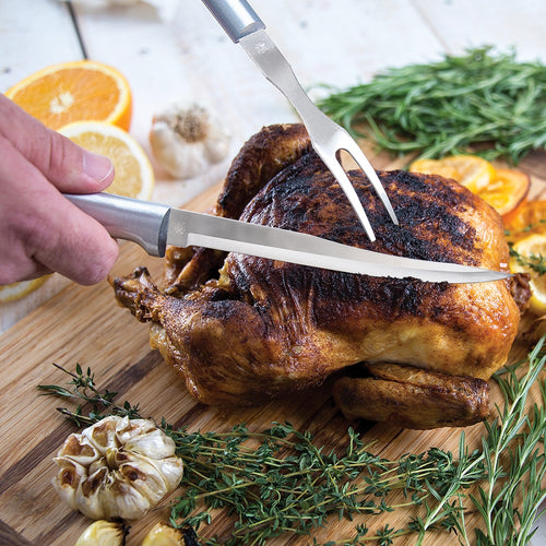 Handcrafted serrated steak knife with sharp surgical-grade stainless steel blade slicing a roasted whole chicken, surrounded by fresh herbs and citrus, ideal for Kitchen & Food and USA Made collections.