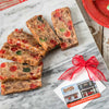 Slices of hand-prepared fruitcake bursting with candied cherries, nuts, and fruit, displayed on marble alongside a festive gift tag, perfect for Kitchen & Food and USA Made collections.