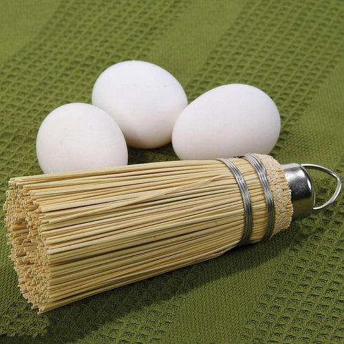 Handcrafted Amish-made miniature straw broom cake tester with metal loop for hanging, shown next to three white eggs on a green textured cloth, part of Kitchen & Food and USA Made collections.