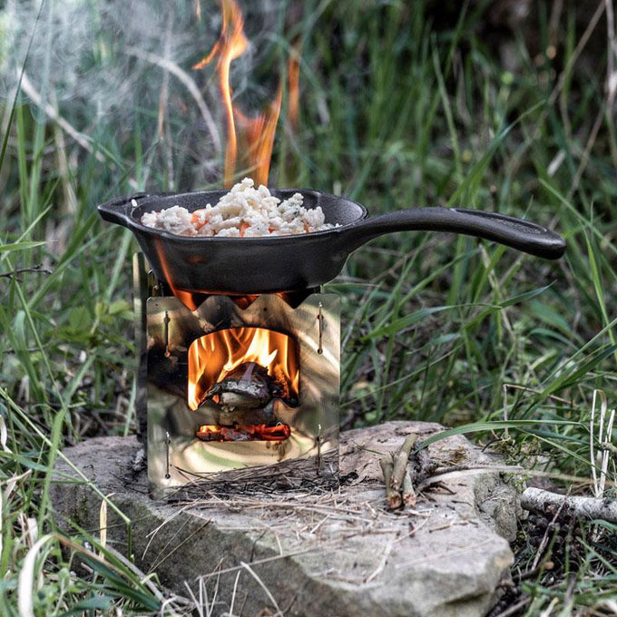Black cast iron fire skillet with long handle cooking rice over an open flame on a portable stove outdoors, perfect for Farm, Garden & Tool, Camping, Kitchen & Food, Cookware, Cast Iron, and Best Sellers collections.