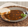 Handcrafted stainless steel soup plate with a wide rim holding vegetable beef soup and a slice of bread, styled on a woven placemat for Kitchen & Food, Dinnerware, and Best Sellers collections.