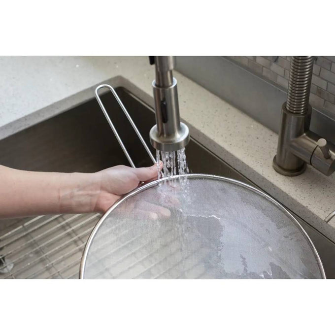 Handheld stainless steel splatter screen being rinsed under running kitchen faucet, designed to protect cooking areas, featured in Kitchen & Food, Kitchen Gadgets, Best Sellers, and Promo Eligible collections.