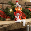 Posable vintage-style Christmas pixie elf ornament in red and white fabric with striped tights and a festive pom-pom hat, displayed on a rustic wooden mantel with holiday greenery and lights, ideal for Home & Decor and Holiday Decor collections.