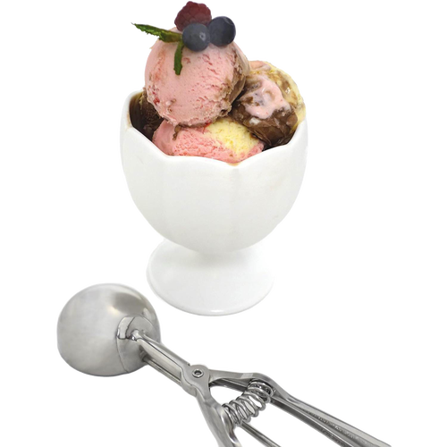 Stainless steel scoop with spring handle resting next to a white ceramic dessert cup filled with three scoops of ice cream garnished with fresh berries, handcrafted for Kitchen & Food, Cookware, Baking Supplies, Kitchen Gadgets, and Best Sellers collections.