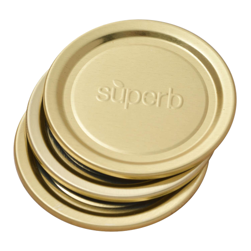 Stack of gold-tone metal regular-mouth canning jar lids embossed with “superb,” featuring BluSeal™ integrity for enhanced sealing, part of USA made kitchen and food preservation collections.