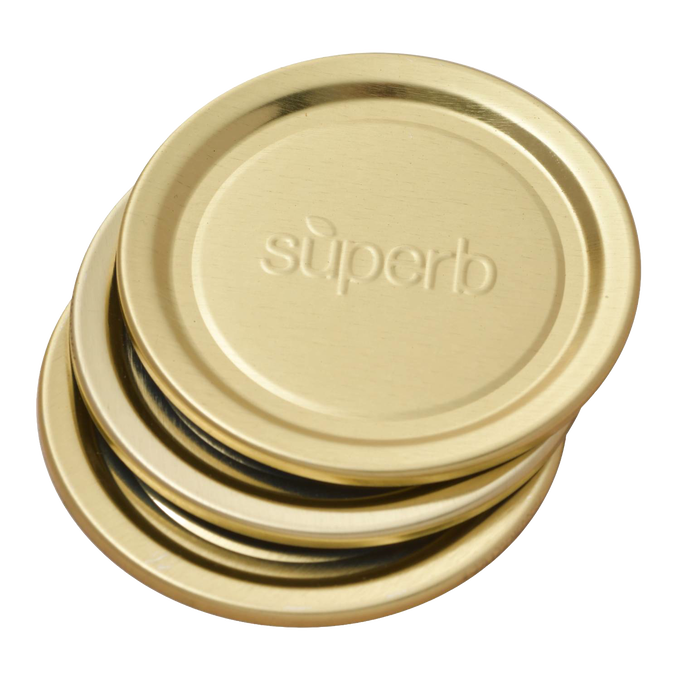 Stack of gold-tone metal regular-mouth canning jar lids embossed with “superb,” featuring BluSeal™ integrity for enhanced sealing, part of USA made kitchen and food preservation collections.