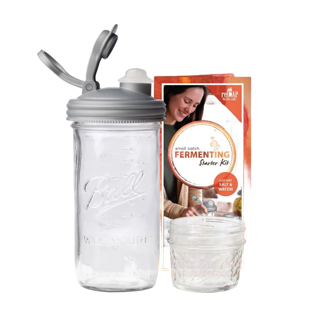 Clear wide-mouth glass jar with a gray fermentation lid and waterless airlock next to a small Mason jar and instructional packaging, ideal for kitchen fermenting and food preservation, USA made.