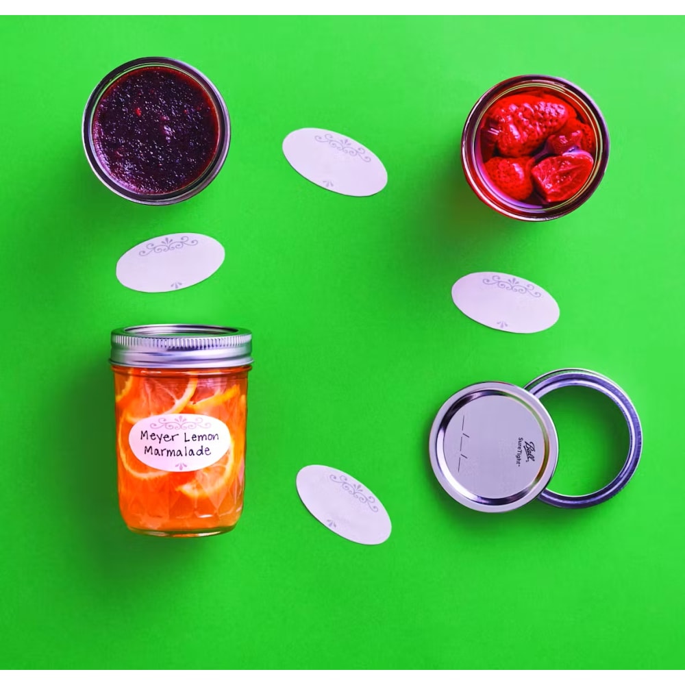 Set of dissolvable oval labels with decorative borders displayed alongside jars of homemade preserves and canning lids on a bright green background, suited for Kitchen & Food, Food Preservation, Canning Accessories, USA Made, and Best Sellers collections.
