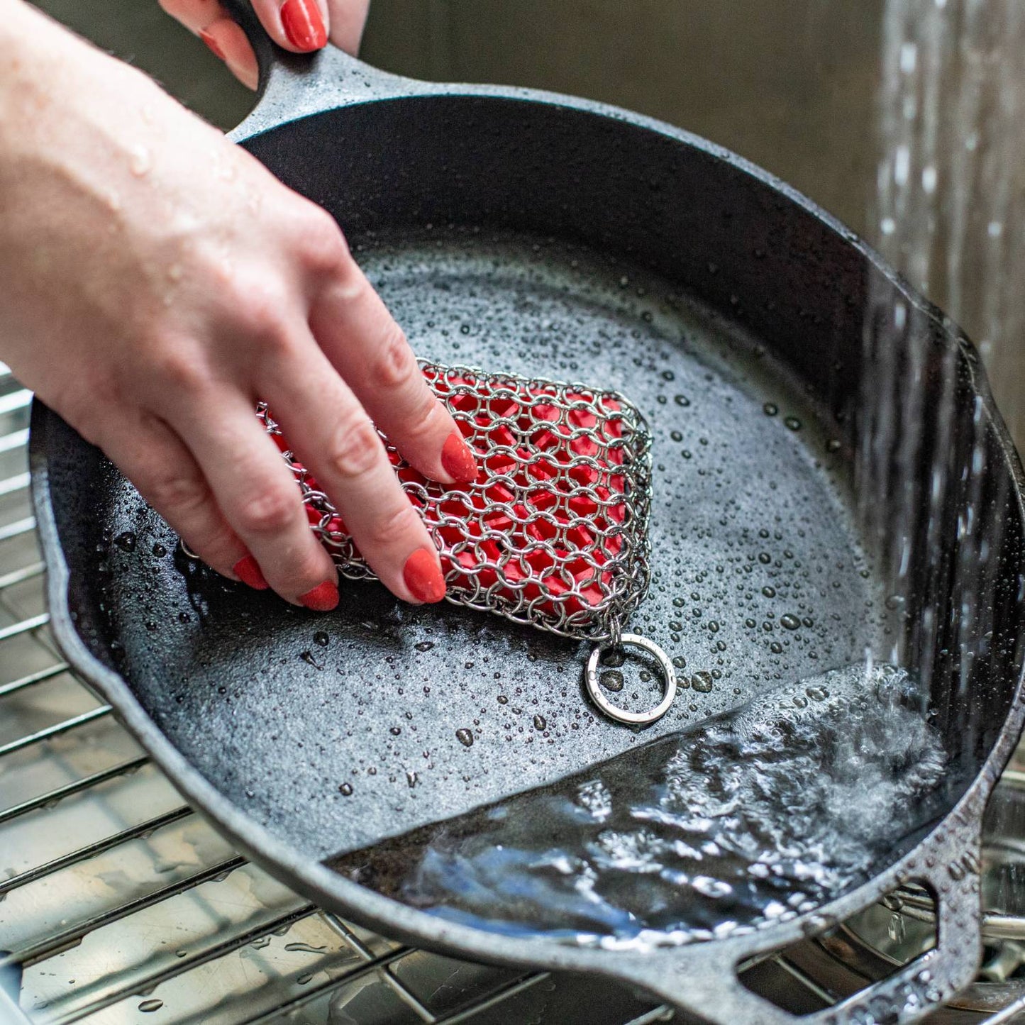 Handcrafted chainmail scrubbing pad with durable stainless steel rings, gently cleaning cast iron cookware under running water in Kitchen & Food and Household Cleaning collections.