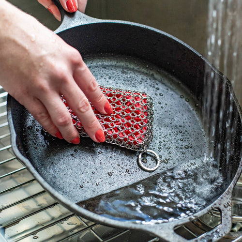Handcrafted chainmail scrubbing pad with durable stainless steel rings, gently cleaning cast iron cookware under running water in Kitchen & Food and Household Cleaning collections.