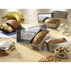 Set of four handcrafted mini loaf pans made in USA arranged with freshly baked bread, surrounded by baking ingredients in a warm kitchen setting, featured in cookware and baking supplies collections.