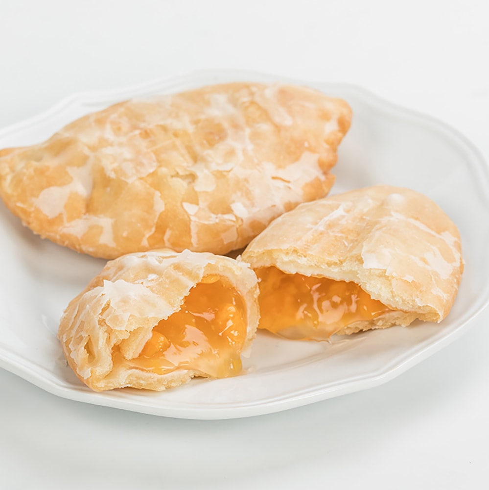 Golden-brown handcrafted Amish fry pies with flaky crusts and sweet apricot filling on a white plate, perfect for Kitchen & Food, Snacks and Sweets, USA Made, and Best Sellers collections.