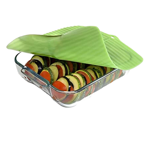 Translucent green reusable silicone bowl cover with banana leaf design sealing a glass dish filled with layered sliced vegetables, ideal for Kitchen & Food, Storage and Serving collections.