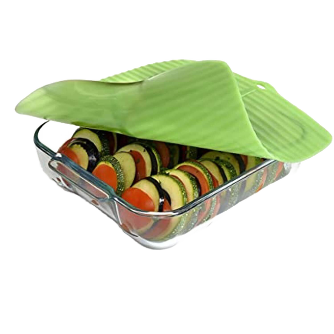Translucent green reusable silicone bowl cover with banana leaf design sealing a glass dish filled with layered sliced vegetables, ideal for Kitchen & Food, Storage and Serving collections.