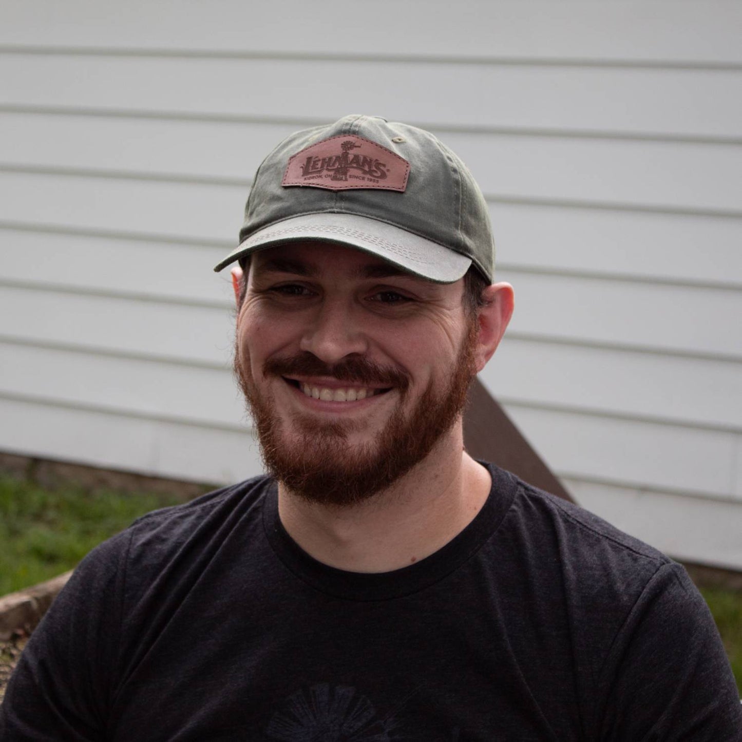Man smiling outdoors wearing an adjustable vintage-style cap with a weathered cotton finish and a light brown leather patch featuring a windmill, ideal for Health & Wellness, Clothing and Accessories, Best Sellers, and Promo Eligible collections.