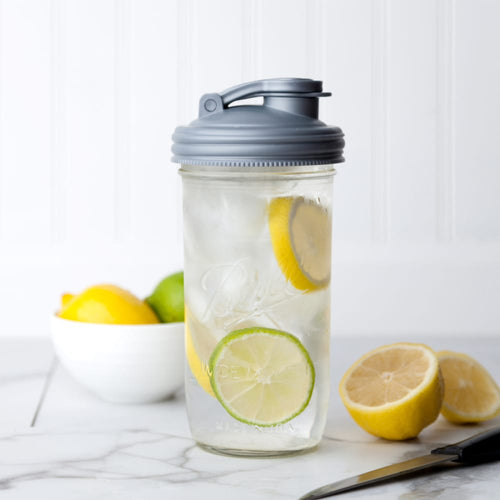 Gray pour lid with flip-top spout and carry loop fitting a wide-mouth mason jar filled with iced citrus water, featured in Kitchen & Food, Dinnerware, Kitchen Gadgets, USA Made, and Best Sellers collections.