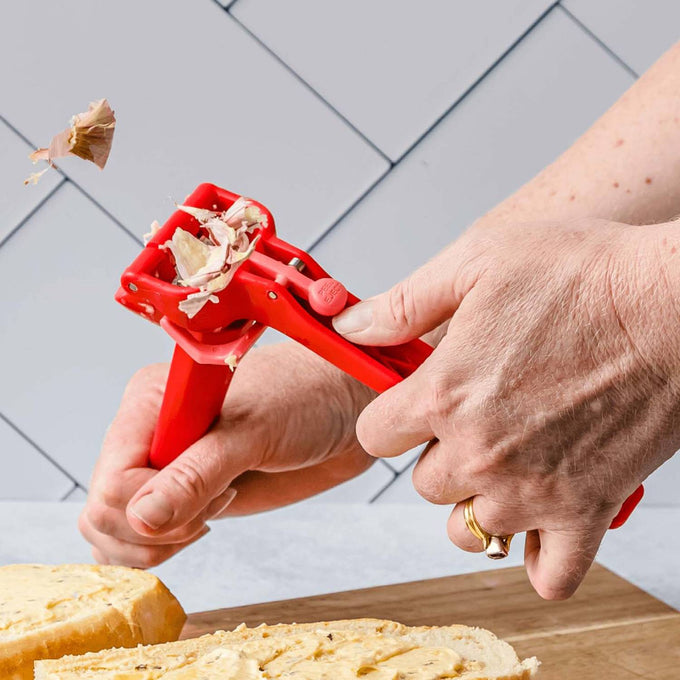 Red garlic press with an easy-press design that minces multiple unpeeled cloves and ejects the peel for hands-free garlic prep, featured in Kitchen & Food, Food Prep, and Kitchen Gadgets collections.