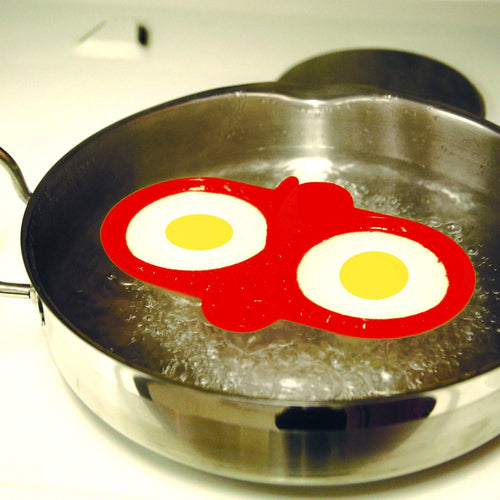 Red high heat resistant silicone double egg poacher with two eggs cooking simultaneously in a stainless steel skillet, ideal for kitchen gadgets and cooking helpers collections.