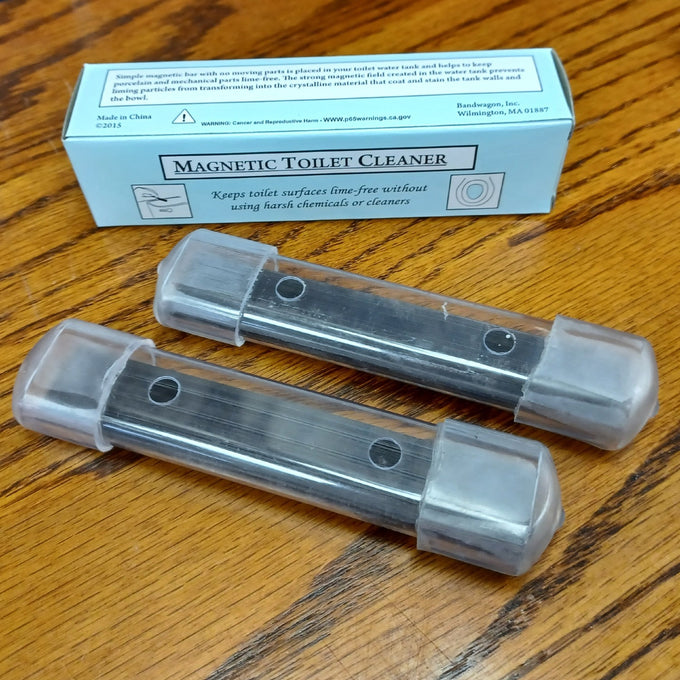 Two clear plastic housings containing long-lasting magnets designed to prevent mineral buildup and stains in toilet tanks, shown with a labeled box on a wooden surface, part of Home & Decor and Household Cleaning collections.