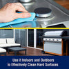 Hand wiping a stainless steel stove burner with a blue cloth paired with a clean outdoor patio featuring a gas grill and seating on a wooden deck, illustrating versatile household cleaning for indoor and outdoor hard surfaces.