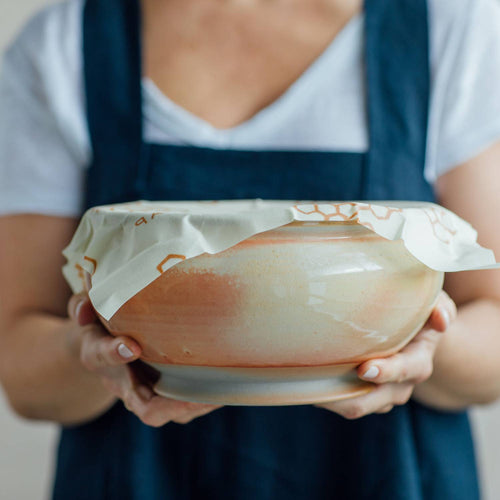 Handmade large beeswax food wrap with honeycomb pattern covering a round ceramic bowl, eco-friendly and reusable for food storage, part of Kitchen & Food, Storage and Serving, USA Made, and Best Sellers collections.
