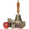 Shiny brass bell with a long wooden handle, displayed atop vintage books alongside a red apple and wooden alphabet blocks, representing classic home and decor style.