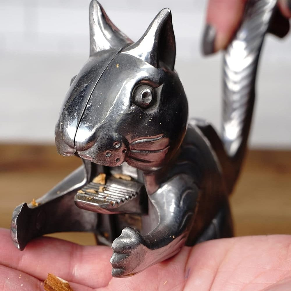 Handcrafted cast aluminum squirrel nutcracker lifting its tail to crack nuts, shown in use on hand with nut shells, featured in Kitchen & Food, Food Prep, Choppers and Cutters, Best Sellers collections.