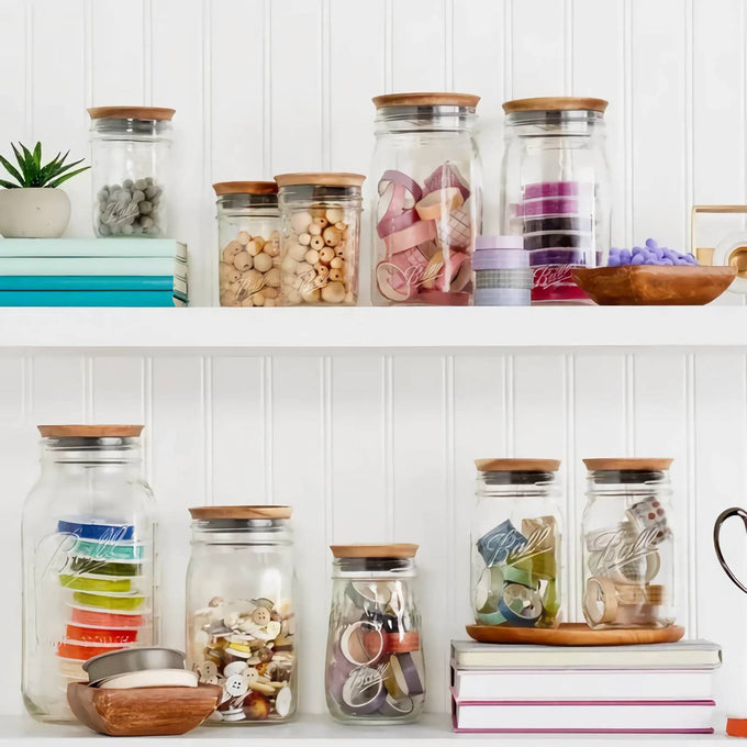 Set of clear glass jars with airtight acacia wood lids in various sizes, filled with craft supplies and kitchen items, displayed on white shelves in Kitchen & Food and Storage collections.